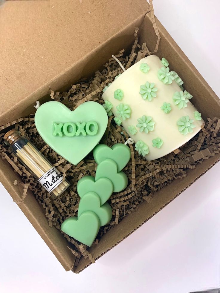 an open box with some green decorations and a cake in the shape of a heart