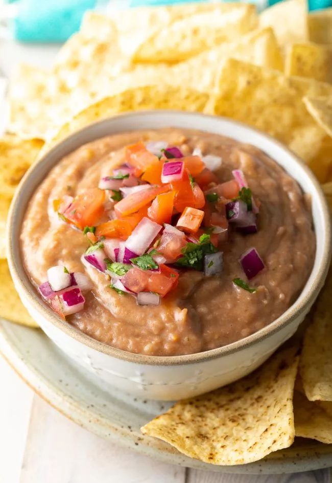 a white bowl filled with guacamole surrounded by tortilla chips and salsa