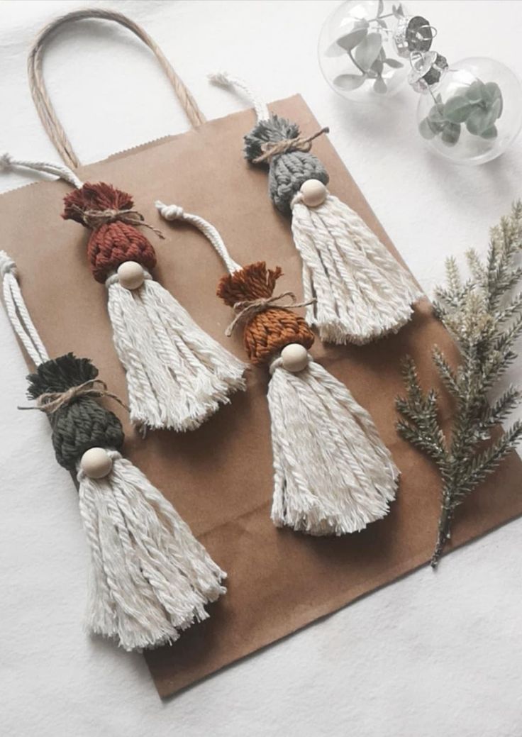 four tasselled ornaments are sitting on a piece of brown paper next to some plants