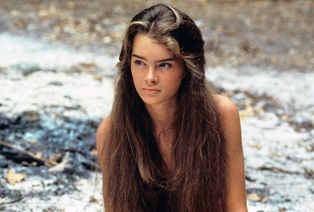 a woman with long hair sitting on the ground