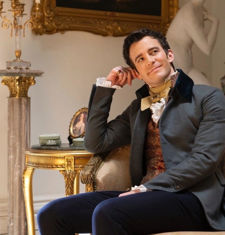 a man sitting on top of a chair next to a table with a clock in the background