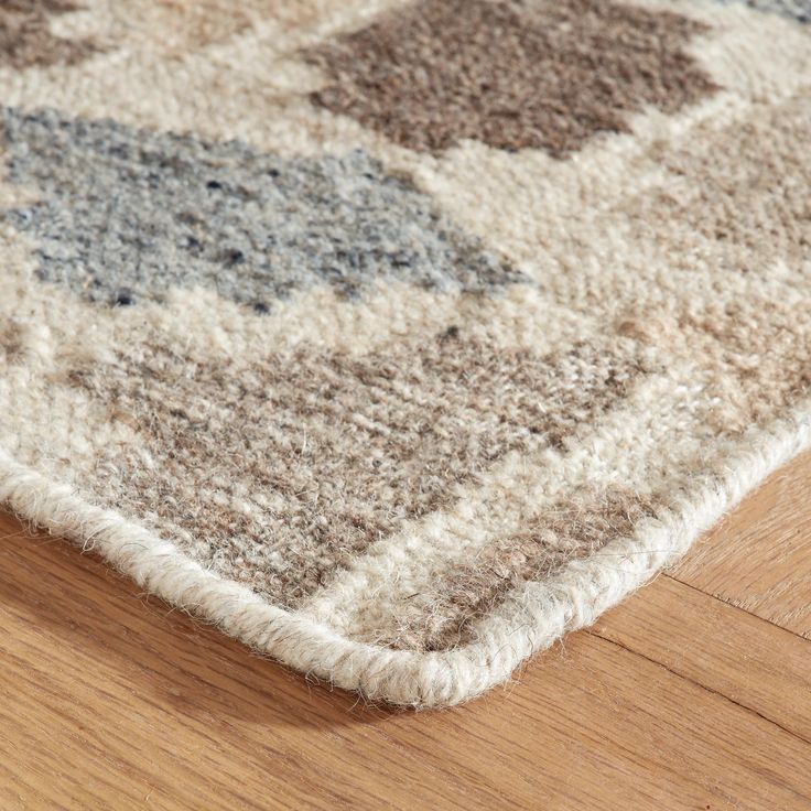 an area rug is laying on the floor with wood and carpeting in the background