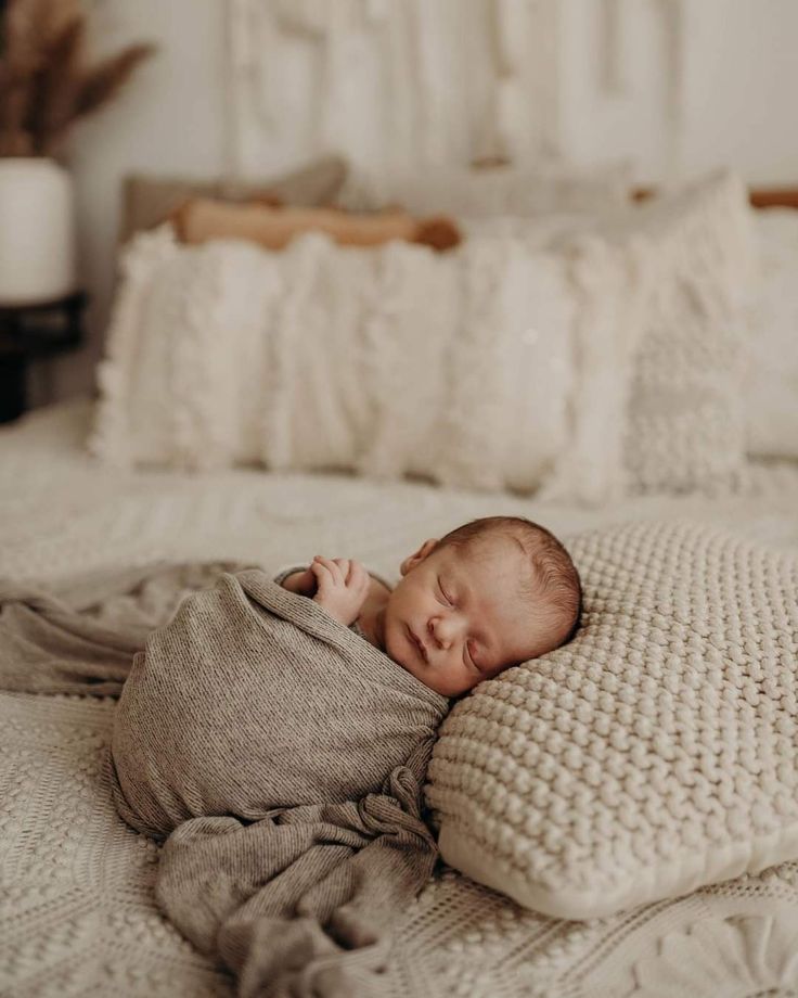 a baby wrapped in a blanket laying on top of a bed