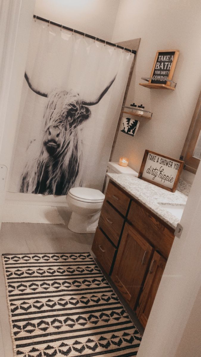 a bathroom with a black and white cow shower curtain in it's stall area