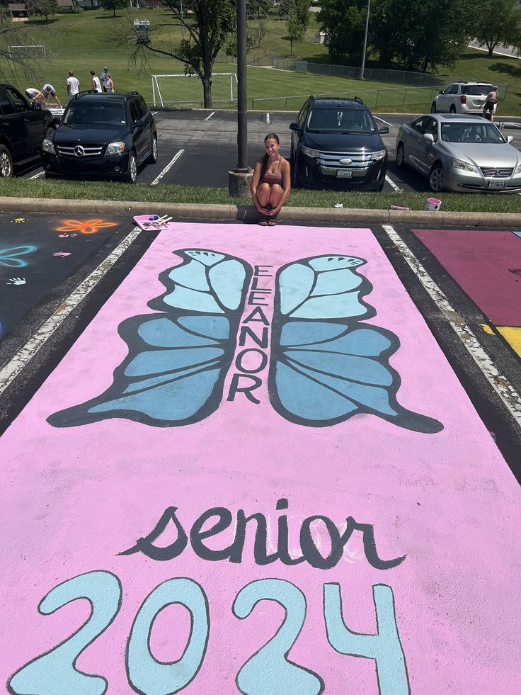 a woman sitting on the side of a parking lot next to a pink sign that reads senior 2094