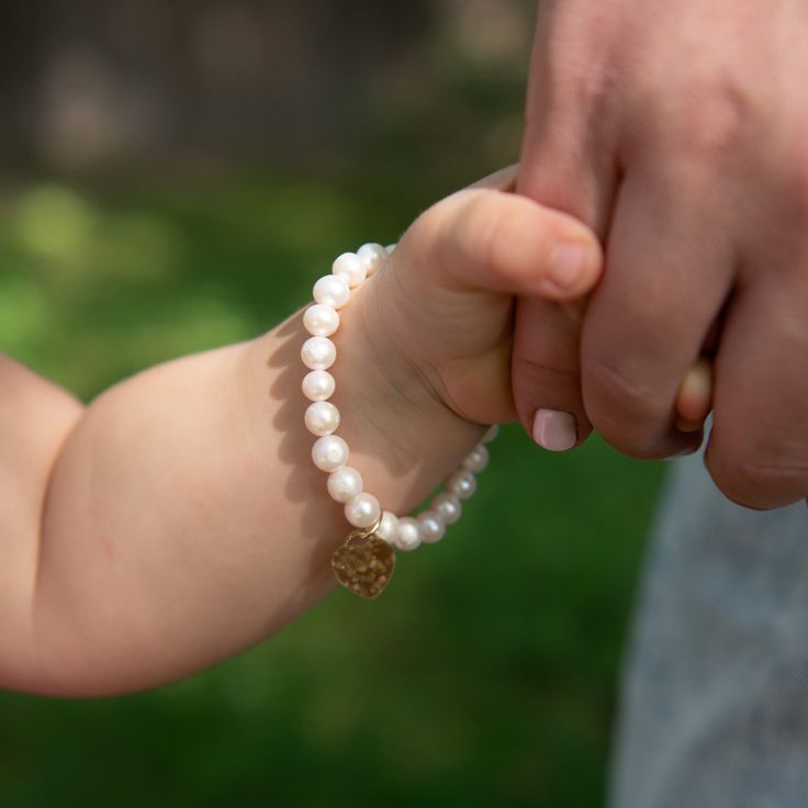 Our favorite classic pearls styled for Mommy & Me. How sweet to dress up with matching bracelets knowing they represent your special love for each other. Bracelets are created with 6mm freshwater pearls and 14k gold filled accent bead. Mommy heart is hand hammered and approximately 1" across. Mini styles have a smaller sized heart approsimately 1/2" across. Easy wear and effortless bracelet stacking with stretch cord design. Bracelet is made to fit an average 7" wrist for mommy. Select your choi Elegant Adjustable Hypoallergenic Heart Bracelet, Elegant Hypoallergenic Adjustable Heart Bracelet, Classic Adjustable White Charm Bracelet, Classic White Adjustable Charm Bracelet, Elegant White Name Bracelet For Mother's Day, Elegant Hypoallergenic Name Bracelet With Round Beads, White Pearl Heart Bracelet With Pearl Charm, Classic Single Strand Beaded Bracelet For Gift, Classic Single Strand Beaded Bracelets As Gift