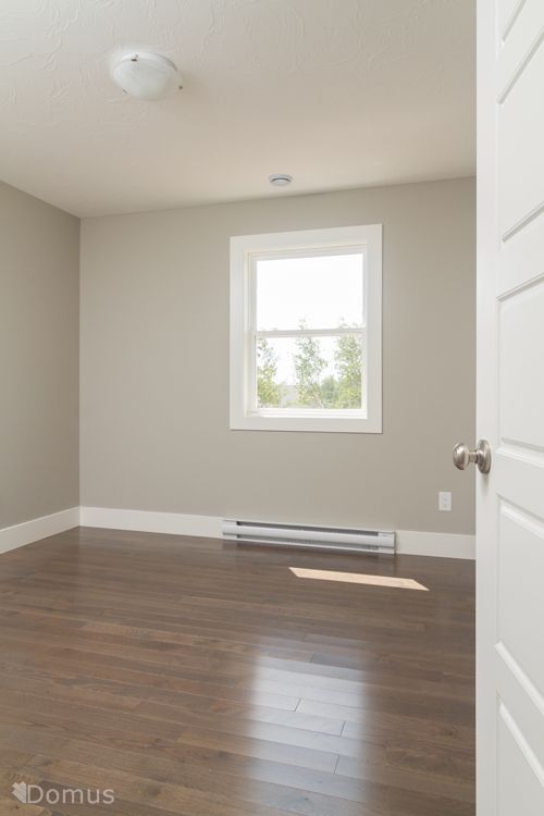 an empty room with hard wood flooring and a white radiator in the corner