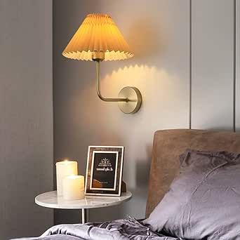 a bedroom with a bed, night stand and lamp on the wall next to it