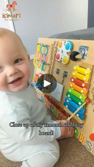 a baby sitting on the floor next to a wooden board with beads and crayons