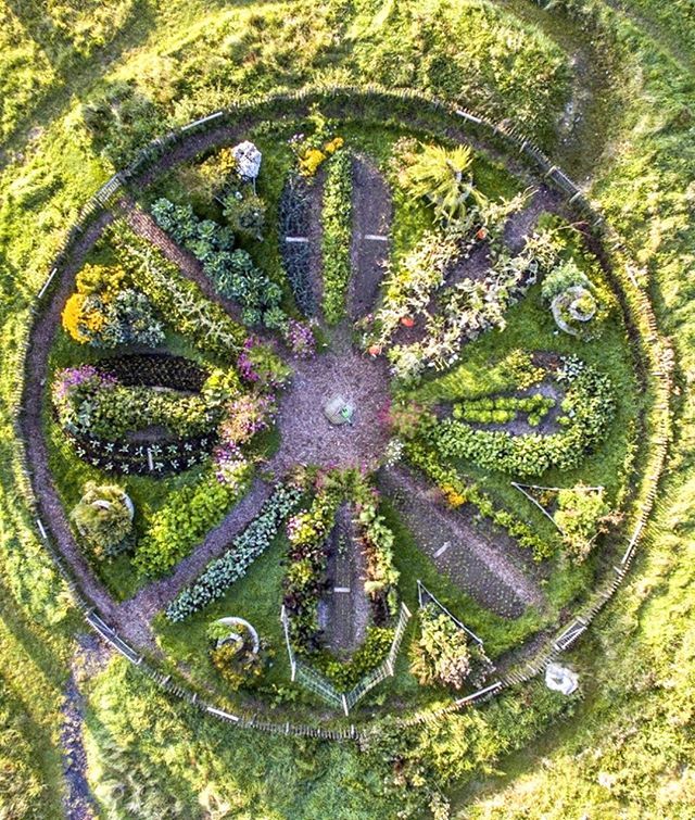 an aerial view of a circular garden in the middle of a grassy area with trees and flowers