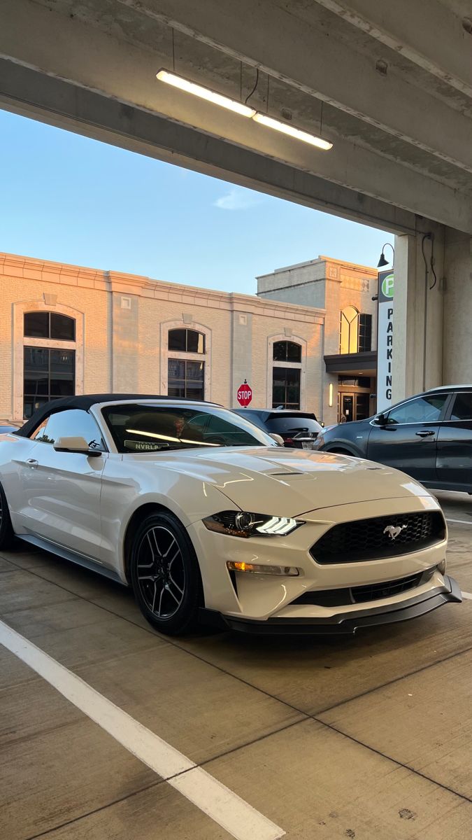 a white mustang parked in a parking garage