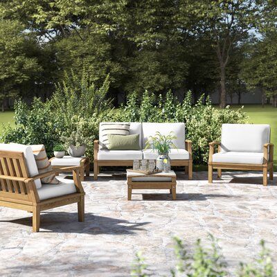 an outdoor seating area with chairs, tables and potted plants on the ground in front of some trees