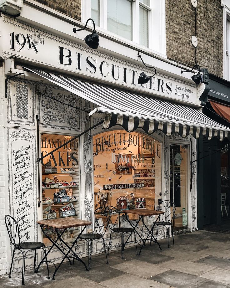 an outside view of a store front with tables and chairs on the sidewalk in front