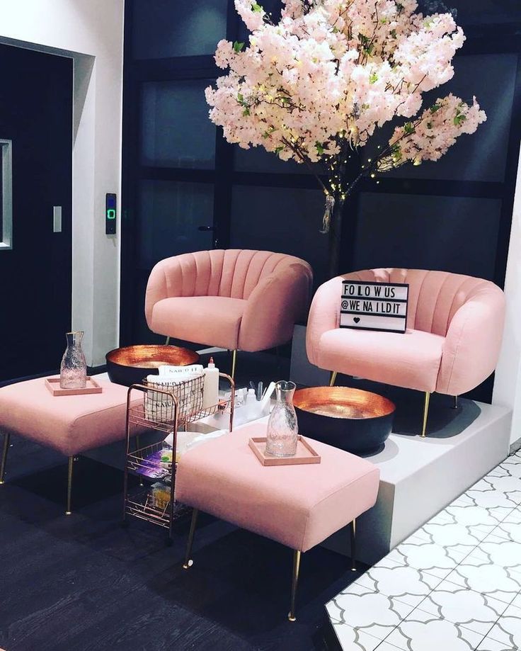 two pink chairs sitting next to each other in front of a vase filled with flowers