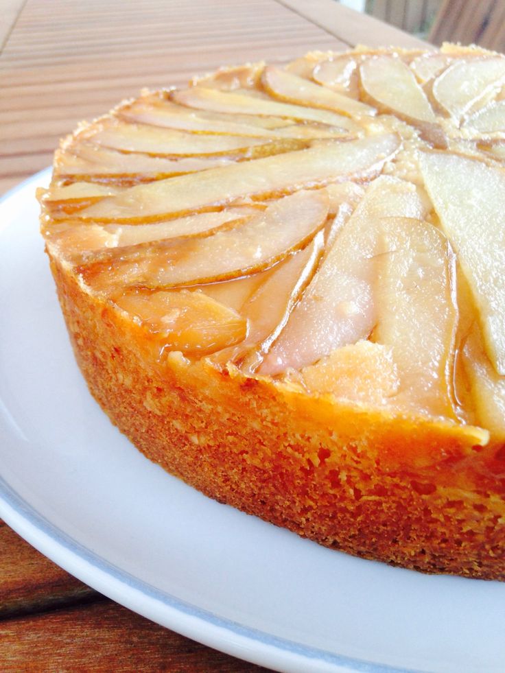 a white plate topped with a cheesecake covered in apple toppings on top of a wooden table