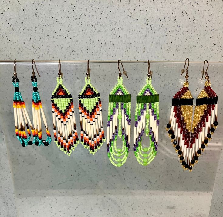 four pairs of beaded earrings hanging from hooks on a glass display case in a store