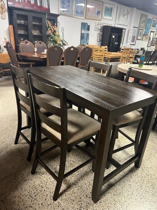 a dining table and chairs in a room with pictures hanging on the wall behind it