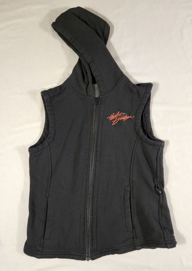 Harley Davidson women's sleeveless hooded full zip vest, size small. This vest is pre-owned. Please see pictures for approximate measurements. Feel free to reach out with any questions. Black Sleeveless Cotton Outerwear, Fitted Black Hooded Vest, Black Fitted Hooded Vest, Black Sleeveless Vest For Outdoors, Black Hooded Vest For Streetwear, Sporty Stretch Hooded Vest, Black Cotton Vest For Winter, Stretch Sleeveless Vest For Outdoor, Casual Hooded Tank Top For Sports