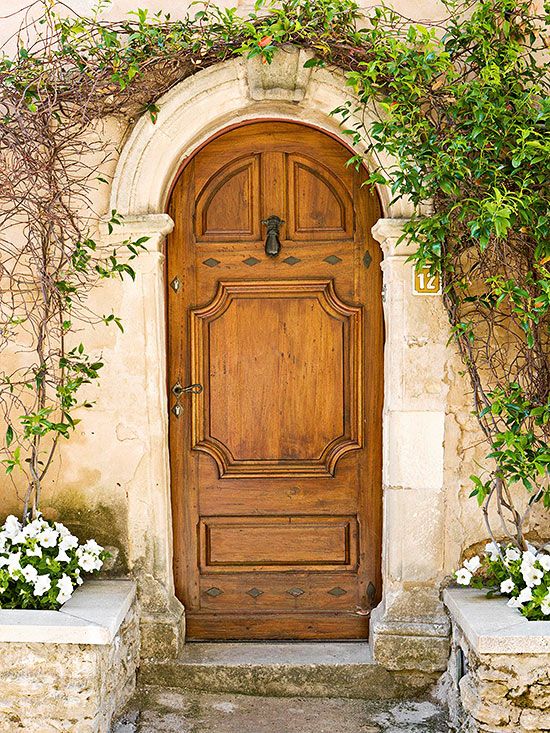 an old wooden door with two planters on either side and flowers in the foreground