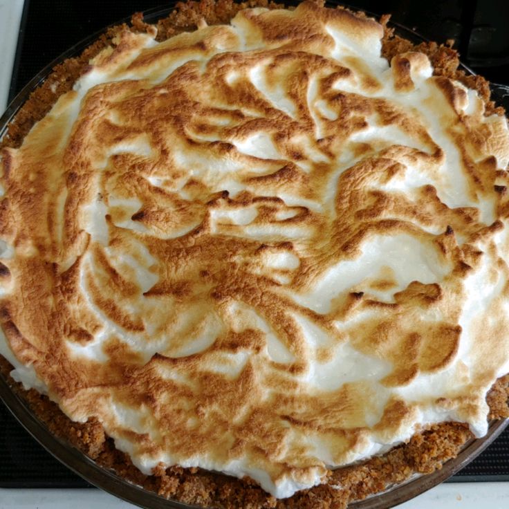 a pie with white frosting on it sitting on top of a stove