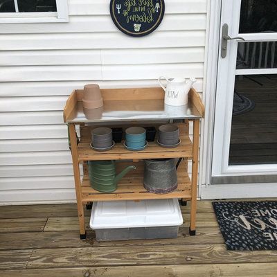 a wooden shelf with pots and pans on it in front of a white house