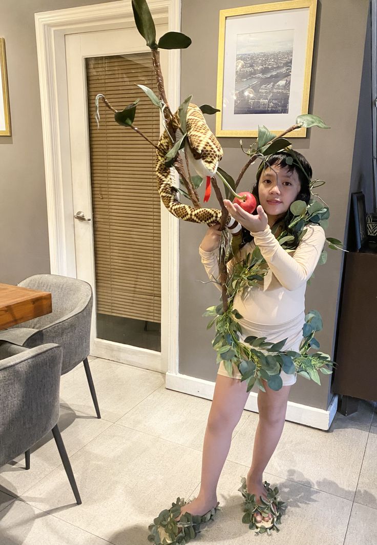 a woman dressed up as a tree branch with leaves on her head and branches attached to her body