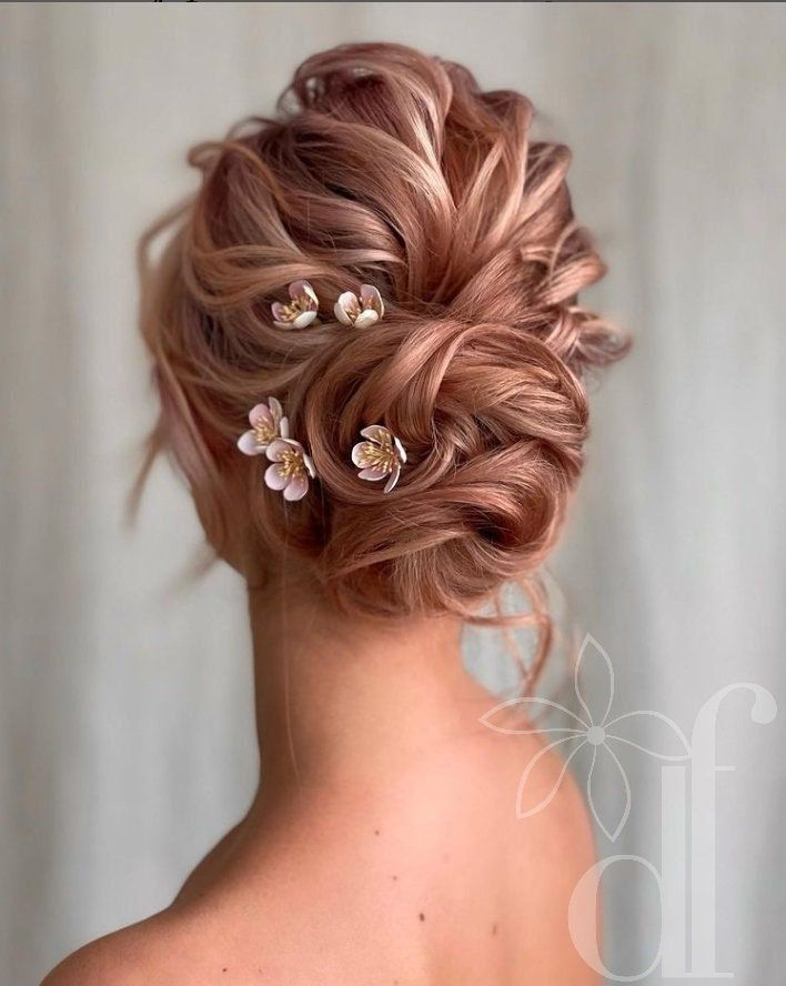 the back of a woman's head, with flowers in her hair and two side braids