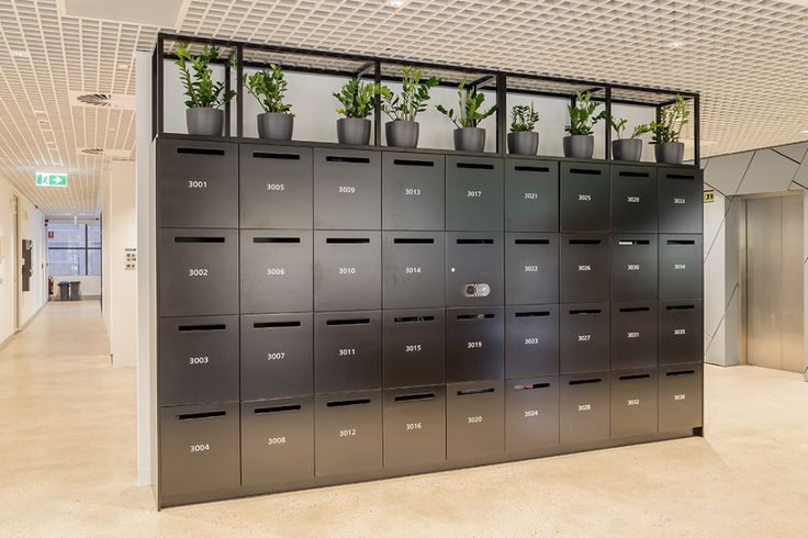 a large metal locker filled with lots of green plants next to a wall mounted elevator