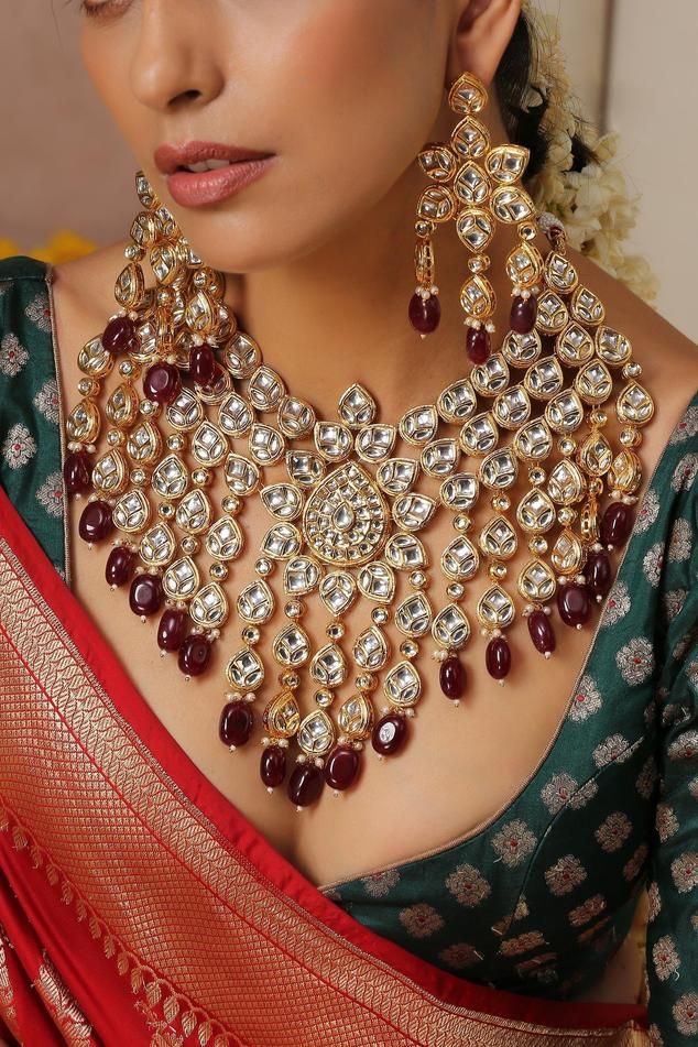 Gold finish long necklace with red kundan embellishment. Comes with earrings and maangtikka.
Component: 1 Necklace, Pair Of Earrings, Maangtikka
Type: Kundan
Composition: Brass
Color: Red
Other Details: 
Geometric motif
Pearl drops
Dimensions L x W (in inches):
Necklace: 19 x 14
Earrings: 3.5 x 2
Weight (in gms): 390
Closure:
Necklace: Pull out-drawcord
Earrings: Push back clasp - Aza Fashions Long Kundan Necklace, Black Bridal Dresses, Red Jewelry Set, Carved Necklace, Long Necklace Set, Kundan Jewellery Bridal, Geometric Motif, Black Bridal, Kundan Earrings