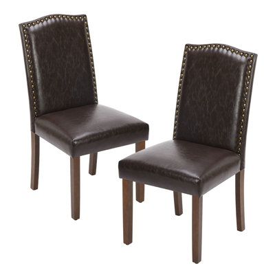 pair of brown leather dining chairs with studded wooden legs and nailhead trimmings