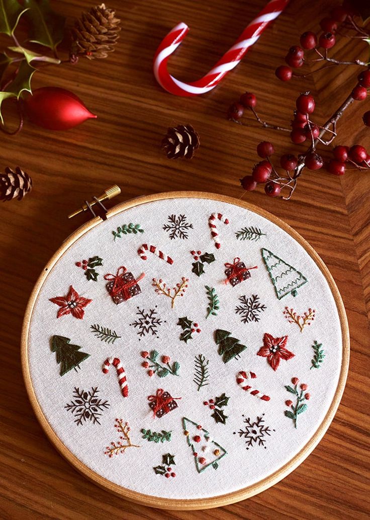 a cross stitch christmas pattern on a wooden table next to candy canes and decorations