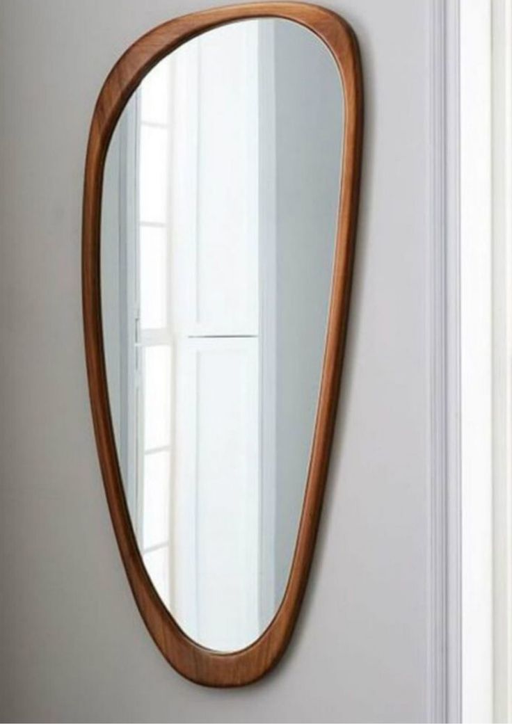 a large wooden mirror hanging on the side of a wall next to a white door