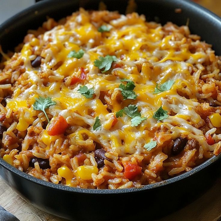 a skillet filled with mexican rice and beans on top of a wooden cutting board