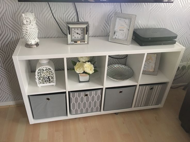 a white entertainment center with grey and gray storage bins