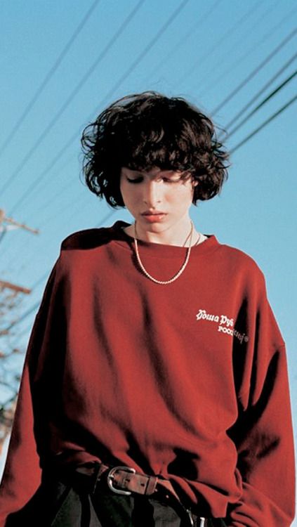 a young man wearing a red sweatshirt and black pants standing in front of power lines