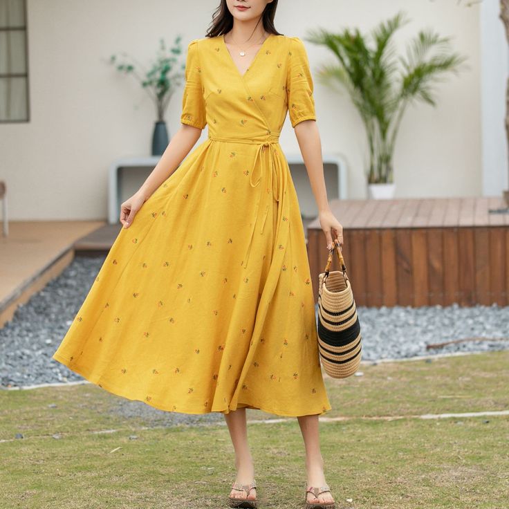 "The dress in the image is a captivating ensemble, perfect for a sunny day out. It's a mid-length, bright yellow dress that exudes cheerfulness with its small floral patterns. The short sleeves and wrap-around design tie at the waist, accentuating the figure, while the V-neckline adds a touch of sophistication. Paired with a straw hat and open-toed sandals, it's an outfit that balances casual comfort with chic style.  DETAILS * 50% linen, 50% cotton blend * Cotton lining on upper part, more comf Summer Floral A-line Dress For Brunch, Summer A-line Floral Dress For Brunch, Spring Vacation A-line Floral Dress, Spring Midi Sundress For Brunch, Summer Brunch Mid-length Maxi Dress, Summer Knee-length Midi Dress For Brunch, Knee-length Midi Dress For Vacation, Summer Brunch Maxi Dress, Floral Print Knee-length Midi Dress For Day Out