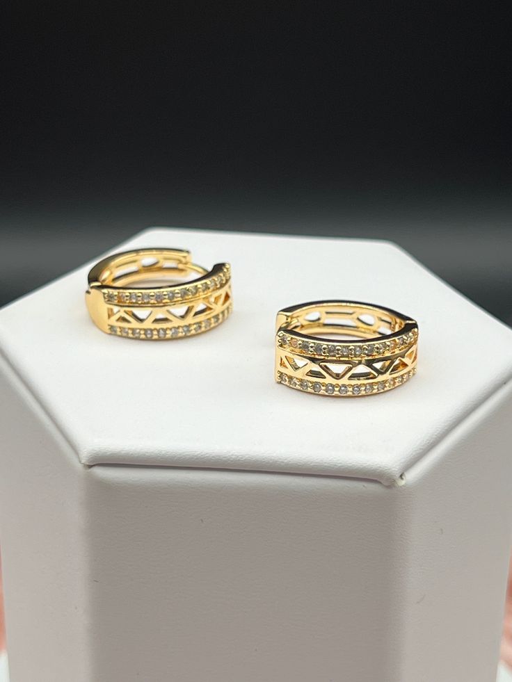 CZ gold huggie earrings are small, close-fitting hoops crafted in lustrous gold, each encrusted with multiple cubic zirconia (CZ) stones that mimic the brilliance of diamonds. Their snug fit around the earlobe and the sparkling CZ stones combine to create a look of understated elegance and timeless sophistication. Cubic Zirconia Huggie Earrings, Gold Huggie Diamond Earrings, Pierced, Classic Cubic Zirconia Huggie Earrings For Pierced Ears, Classic Huggie Earrings With Cubic Zirconia, Anniversary Huggie Diamond Earrings, Gold Huggie Earrings With Pave Setting For Wedding, Gold Huggie Earrings With Diamond Accents, Dazzling Hoop Earrings With Pave Setting In Cubic Zirconia, Gold Cubic Zirconia Diamond Earrings For Anniversary