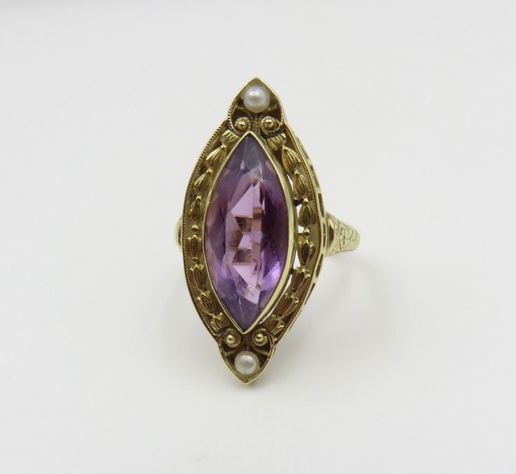 Originally $1,200.00 Circa 1900. Gorgeous Marquis Amethyst ring accented by pearls and beautiful engraving and open work detail in 14KT gold. A very elegant antique cocktail ring. The Bezel set Amethyst measures approximately 18mm x 8mm. The mounting/top of the ring, measures (point to point) approximately 28mm. The width of the mounting is approximately 11mm. The ring is a size 7 3/4 and can be sized. Customer Care: I will help guide you throughout the entire process of your ring selection. I o Antique Yellow Gold Pearl Ring, Antique Oval Pearl Ring Stamped 14k, Antique 14k Gold Amethyst Ring, Antique Pearl Ring With Gemstone, Elegant Marquise Amethyst Ring For Wedding, Elegant Marquise Amethyst Wedding Ring, Antique 14k Stamped Pearl Ring For Wedding, Antique 14k Stamped Pearl Wedding Ring, Antique 14k Gold Pearl Wedding Ring