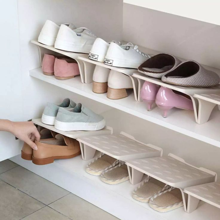 a person reaching for shoes on shelves in a room with tile flooring and white walls