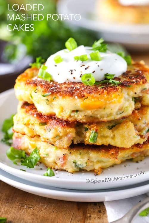 a stack of fritters topped with sour cream and green onions on a white plate