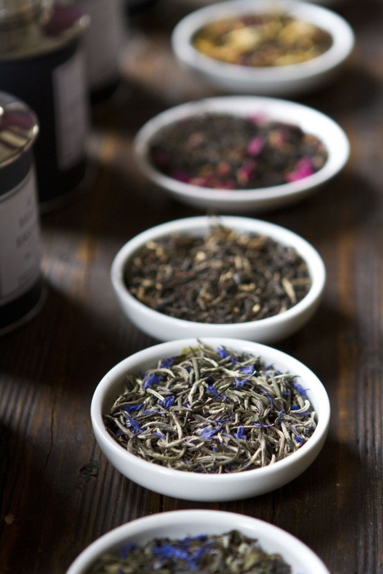 several white bowls filled with different types of tea