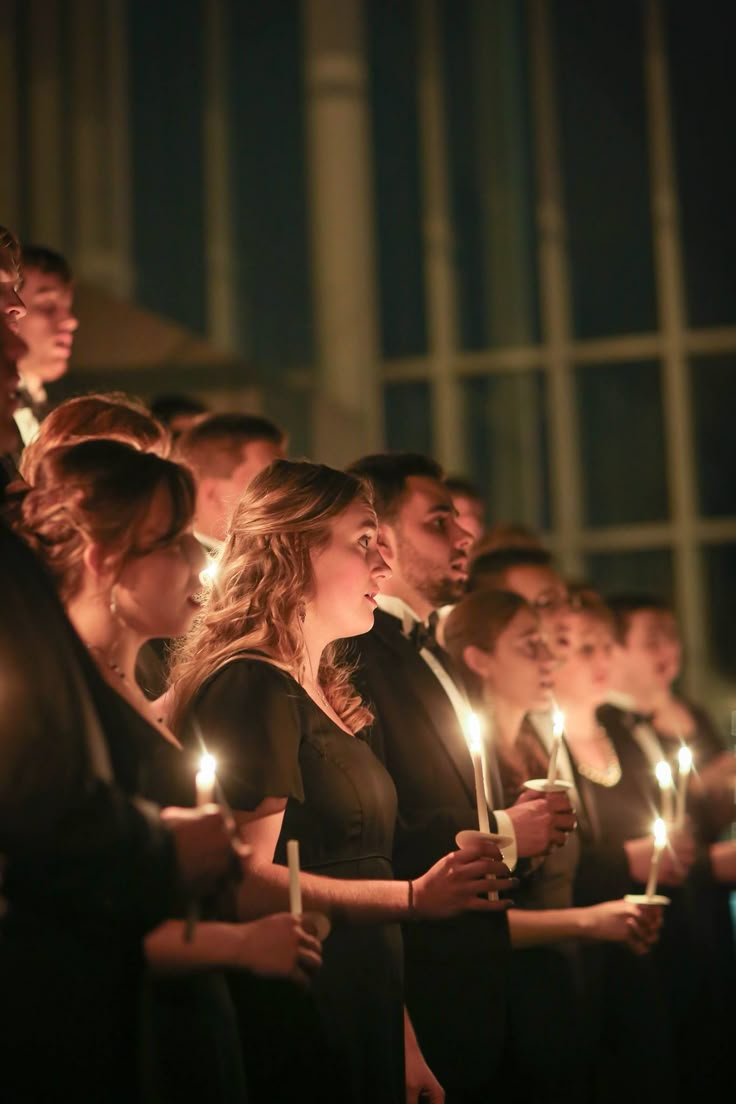 a group of people standing next to each other holding candles