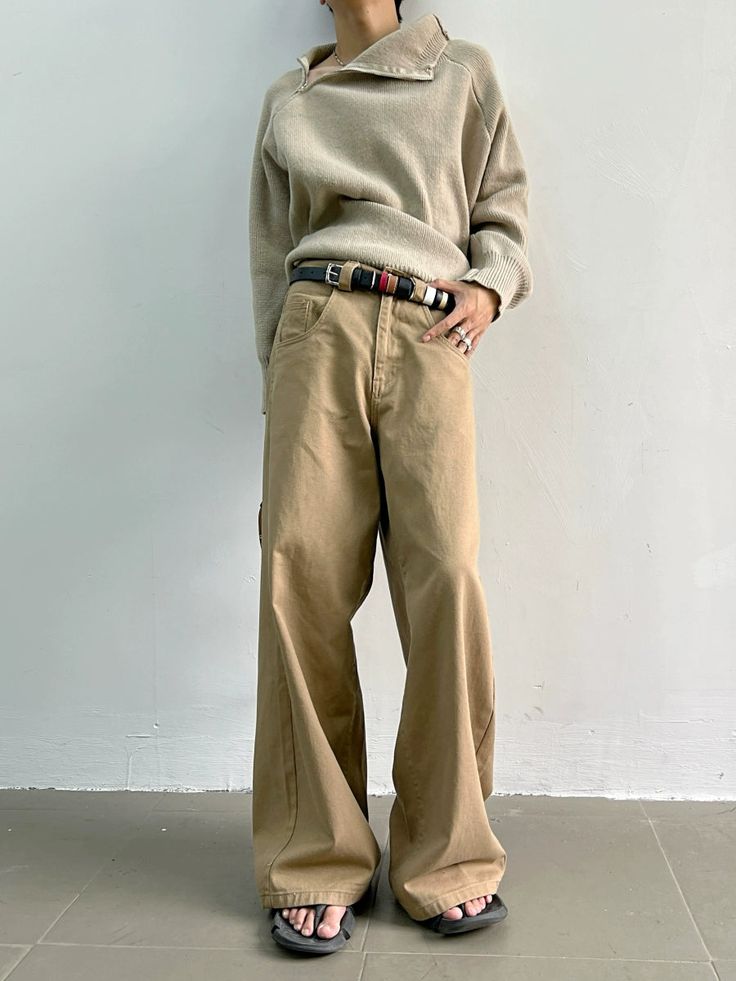 a woman standing in front of a white wall with her hands on her hips wearing wide pants