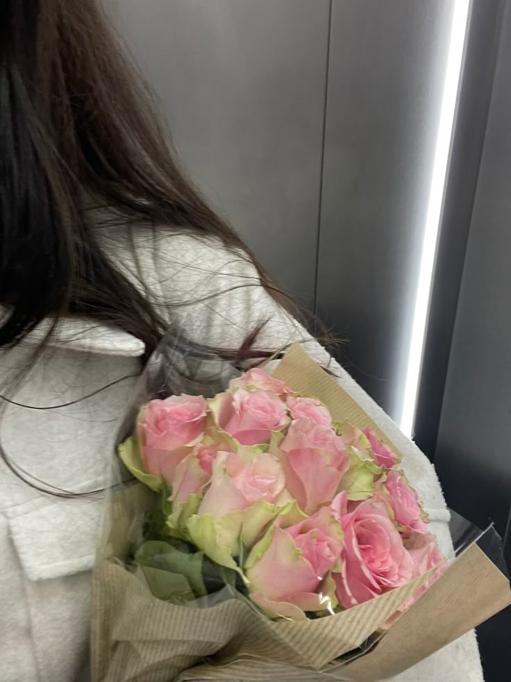 a woman holding a bouquet of pink roses in her hand on an airplane or plane