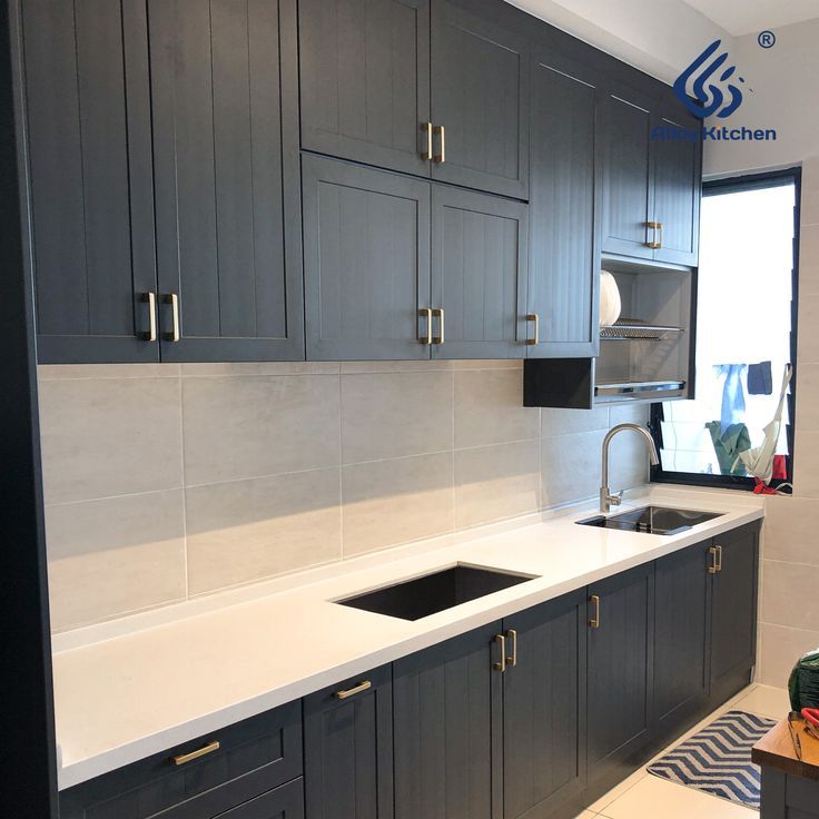 a kitchen with gray cabinets and white counter tops