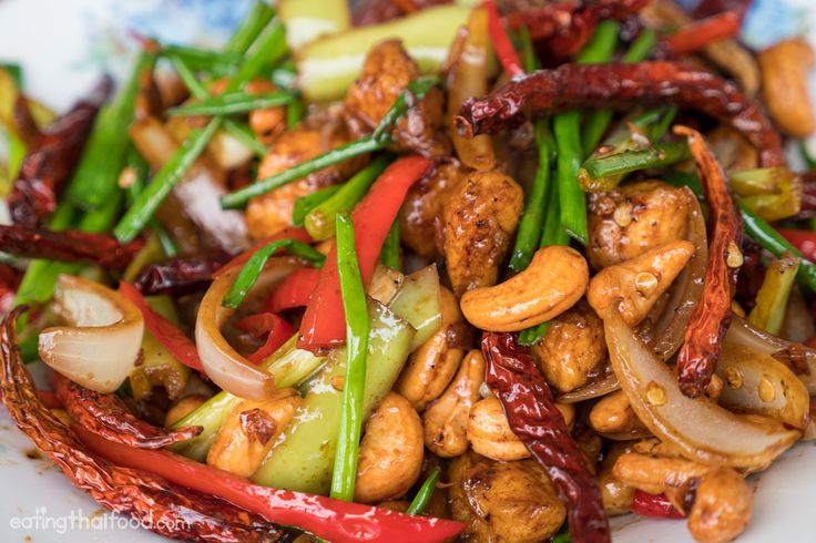 a white plate topped with stir fry vegetables and cashews on top of it