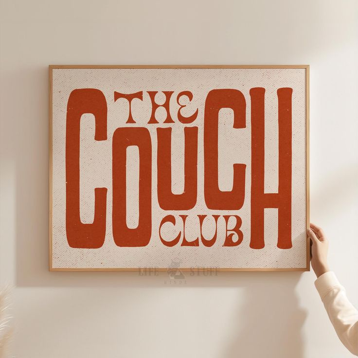 a person holding up a sign that says the couch club on it's wall