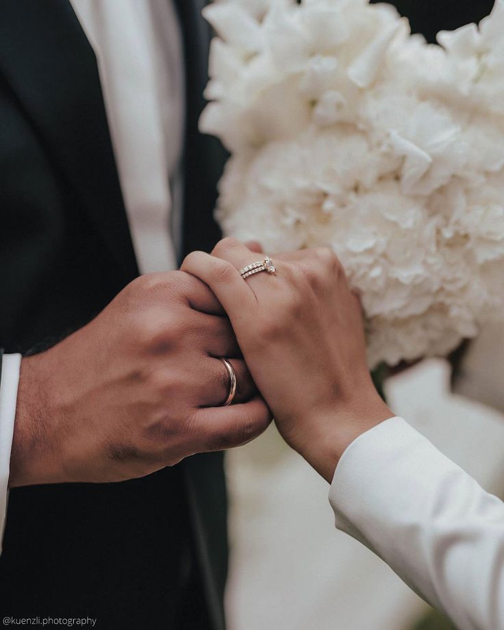 the bride and groom are holding hands with their wedding rings on their fingers while they hold each other's hand