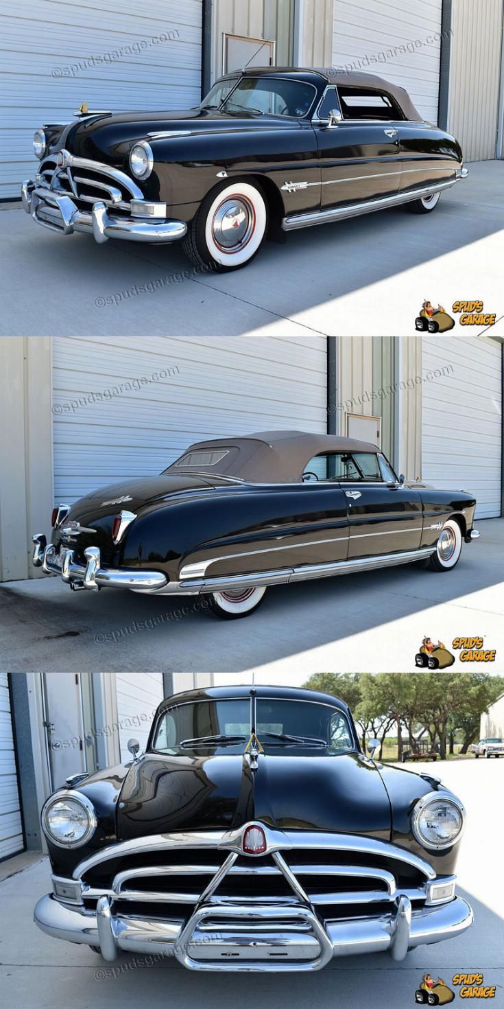 an old black car parked in front of a garage