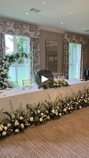 a long table with white flowers and greenery on it